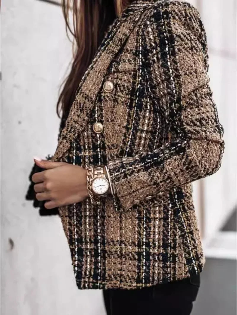 Person wearing a patterned blazer with a watch on a blurred background